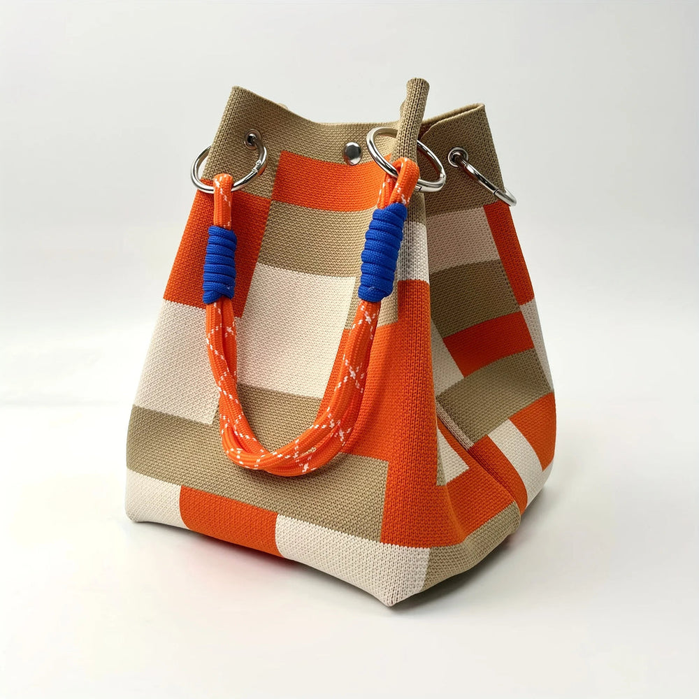 Textured woven bucket bag in orange and beige patchwork design with blue rope handle